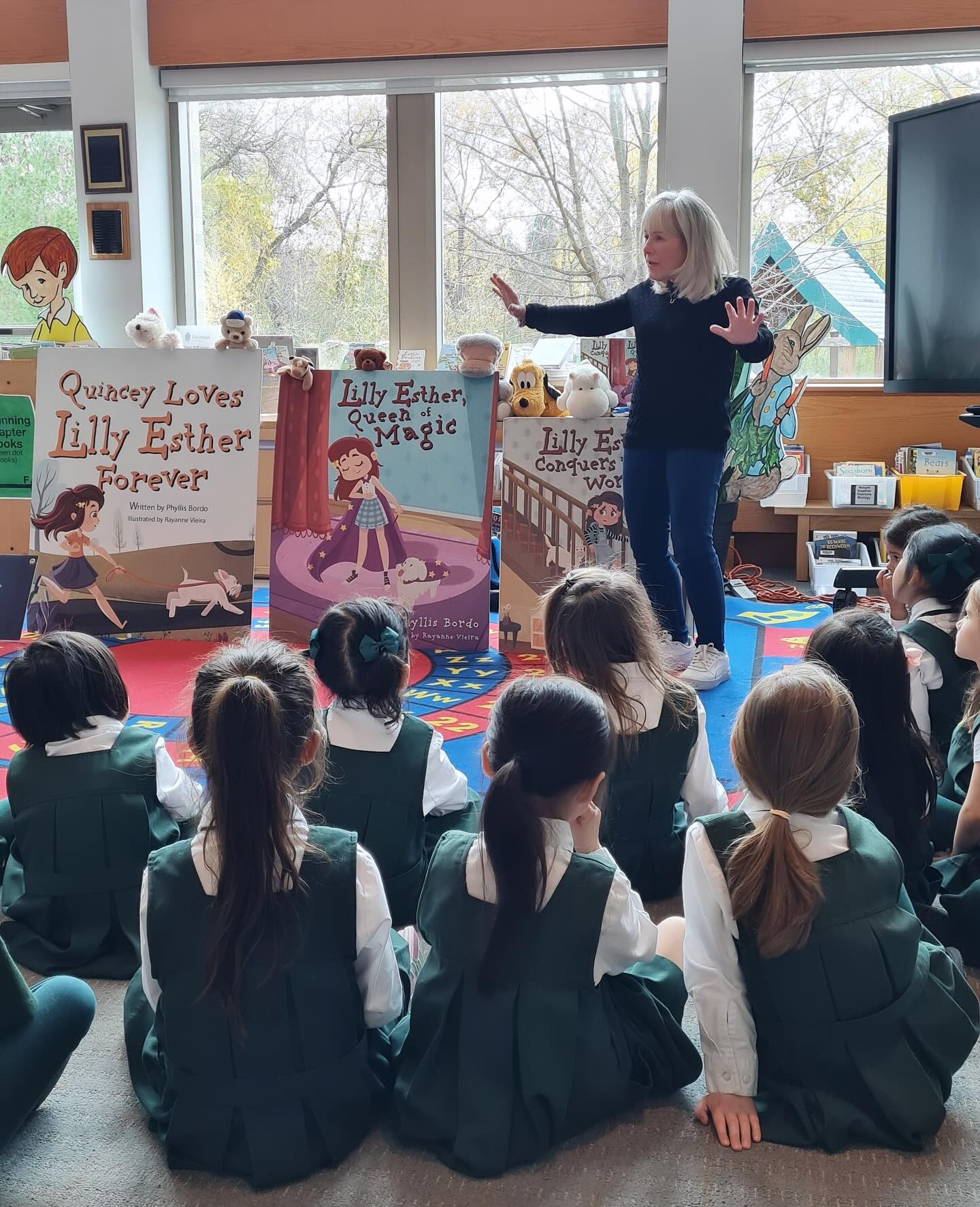 Phyllis reading to students seated on a colourful rug