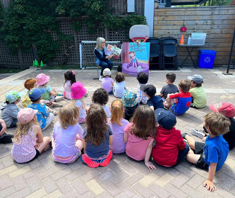 Phyllis reading outdoors to a group of young children